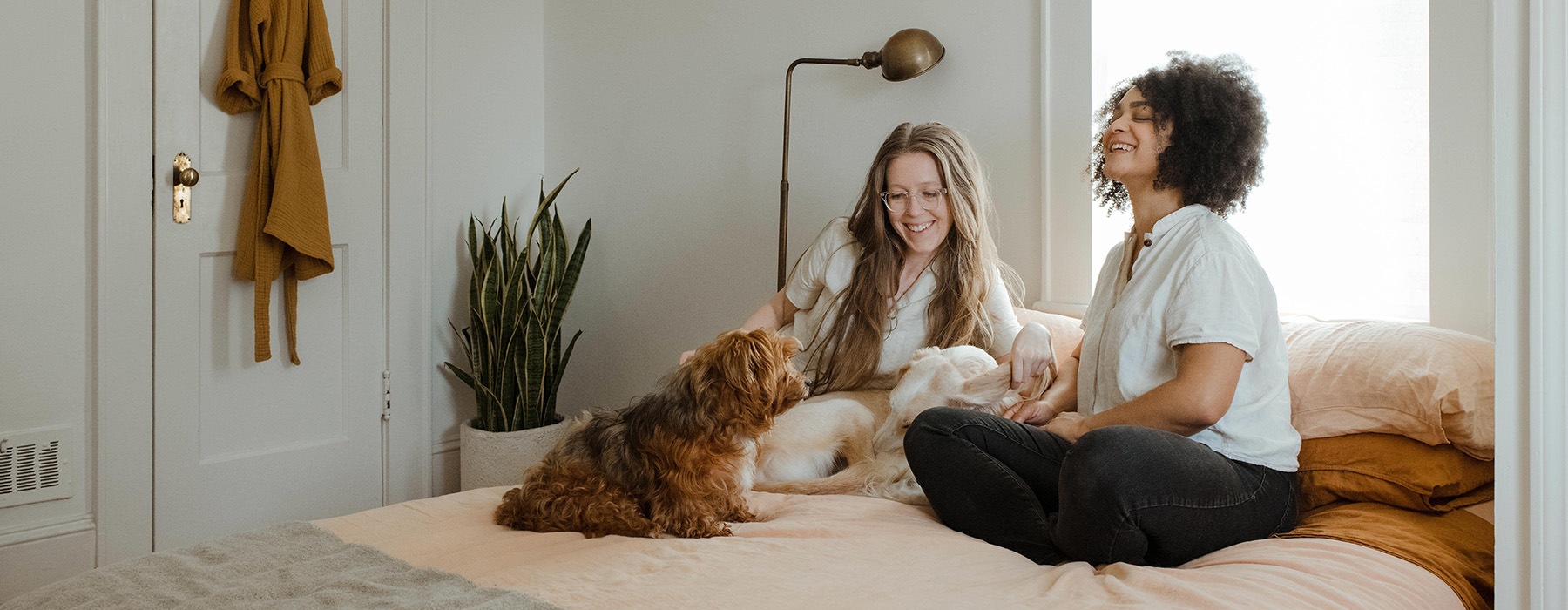 2 people smiling on a bed with a dog